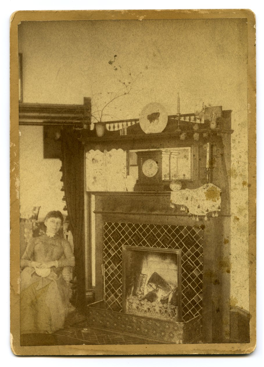 yanan bir şöminenin yanında oturan kadın by Unknown